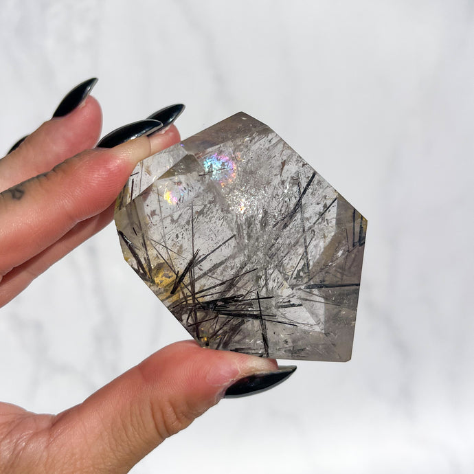 High Grade Quartz crystal with visible inclusions and rainbows against a white background